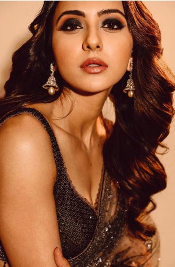 Hairstylist Tina Mukharjee left Rakul's hair in a bunch of brown wavy curls and makeup artist Chakravarthi Kadali added smokey eyes to complete the black vision - Fashion Models