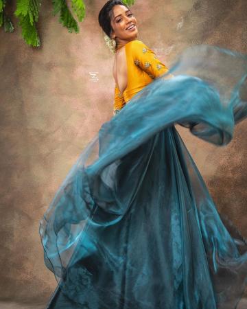 The mustard yellow blouse has a delightful peacock pair motif and the aqua blue skirt falls around her like flowing water - Fashion Models